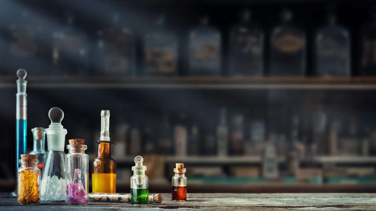 Vintage medications in small bottles on wood desk. Old medical, chemistry and pharmacy history concept background. Retro style.